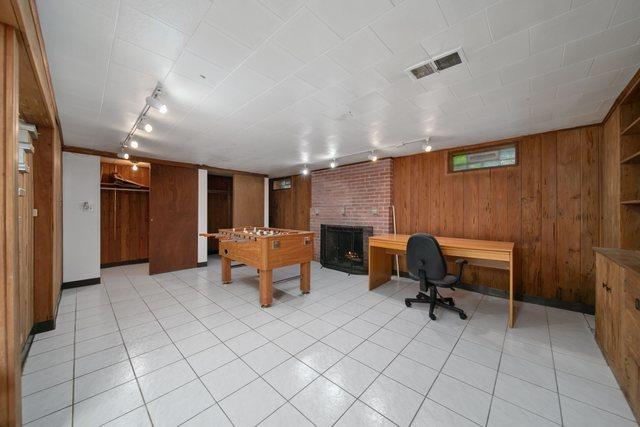 interior space with visible vents, a brick fireplace, wood walls, and rail lighting