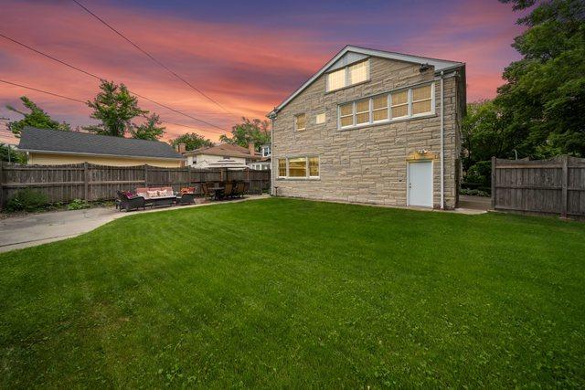 rear view of property with a lawn, a fenced backyard, and a patio area