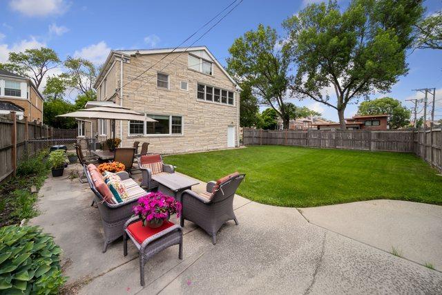 back of property with a fenced backyard, stone siding, outdoor lounge area, a patio area, and a lawn