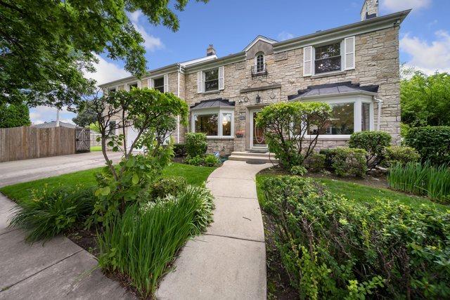 view of front of house featuring stone siding, a chimney, and fence