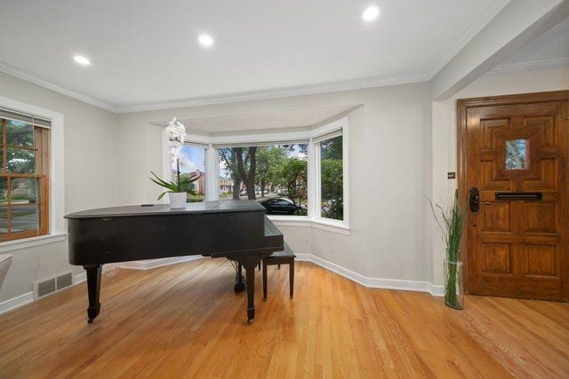 foyer with visible vents, light wood-style flooring, crown molding, and baseboards