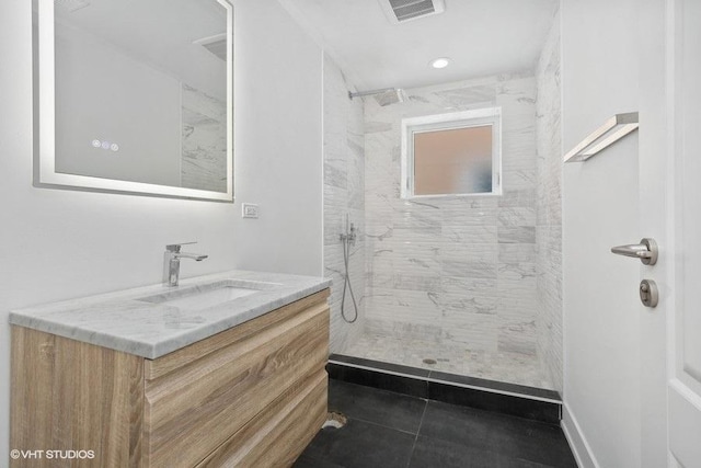 bathroom featuring vanity, tile patterned flooring, and a tile shower