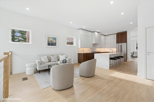 living room featuring sink and light hardwood / wood-style flooring