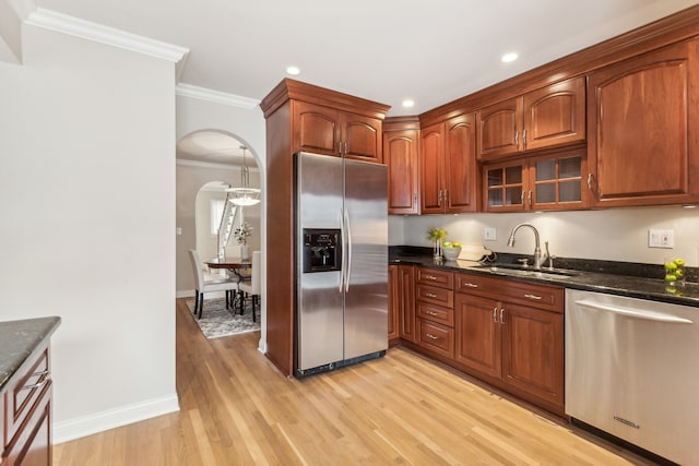 kitchen featuring dark stone counters, light hardwood / wood-style flooring, sink, crown molding, and stainless steel appliances