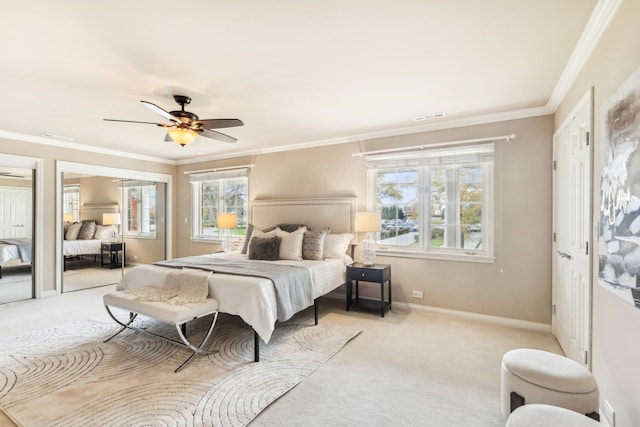 carpeted bedroom with ornamental molding, two closets, and ceiling fan