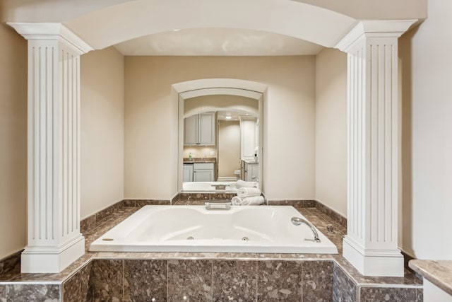 bathroom with vanity, tiled bath, and decorative columns