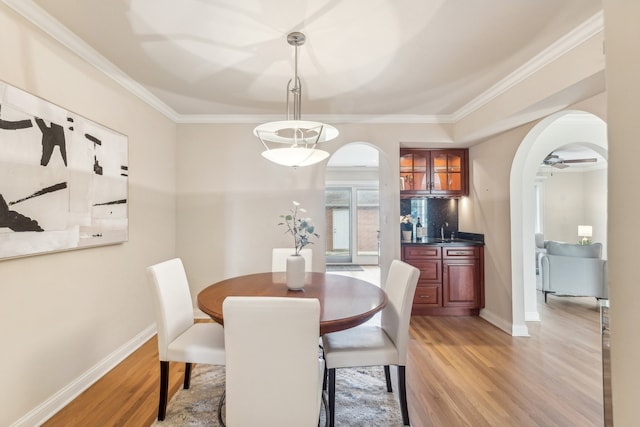 dining space featuring sink, crown molding, light wood-type flooring, and ceiling fan