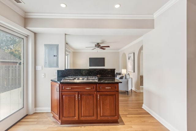 kitchen featuring ceiling fan, light wood-type flooring, ornamental molding, dark stone countertops, and stainless steel gas cooktop