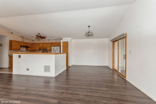 unfurnished living room with lofted ceiling, dark hardwood / wood-style floors, track lighting, and ceiling fan with notable chandelier