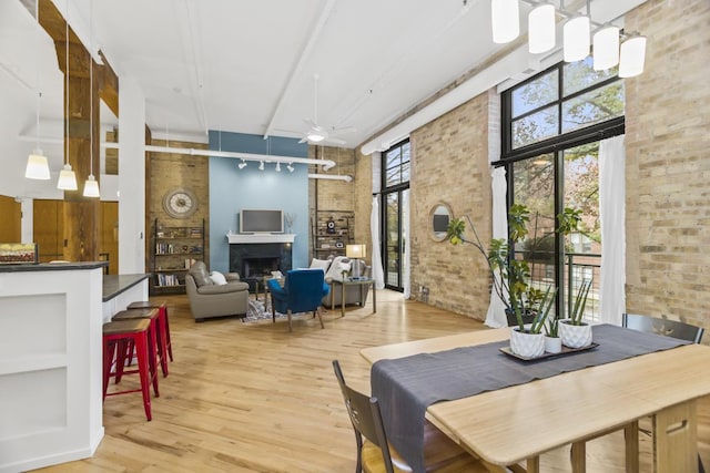 interior space featuring ceiling fan, light wood-type flooring, a towering ceiling, and brick wall