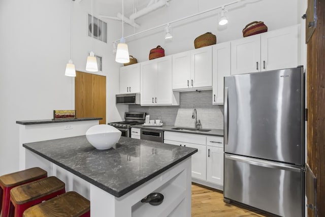 kitchen featuring decorative backsplash, sink, white cabinets, and appliances with stainless steel finishes