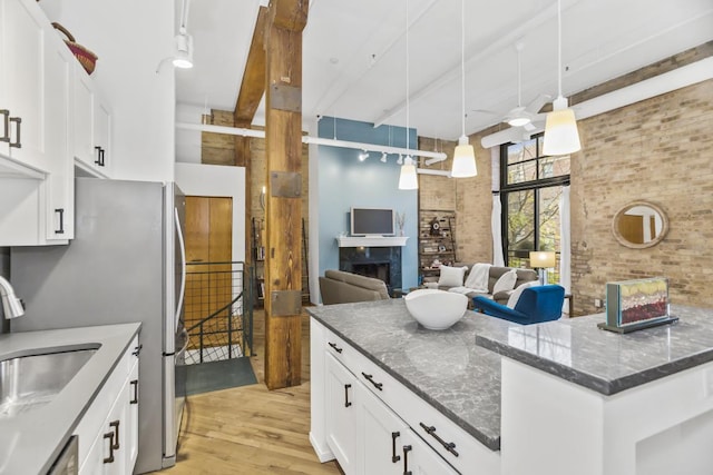 kitchen with brick wall, ceiling fan, pendant lighting, a high ceiling, and white cabinetry