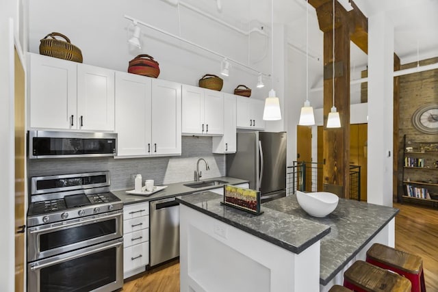 kitchen featuring white cabinets, sink, hanging light fixtures, a kitchen island, and stainless steel appliances