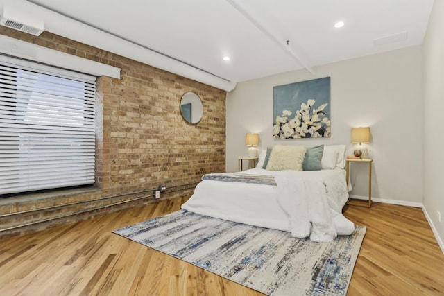 bedroom with hardwood / wood-style flooring and brick wall