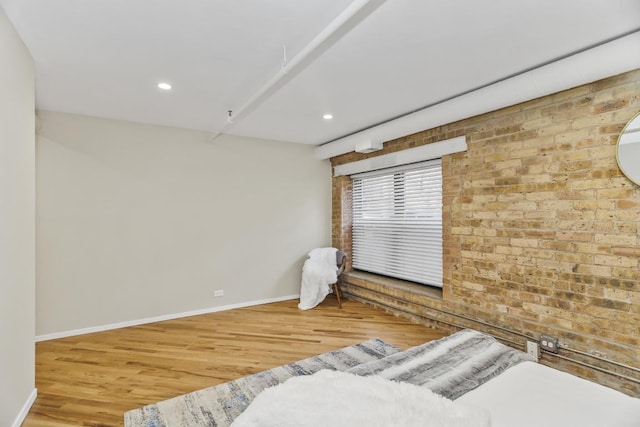 bedroom with hardwood / wood-style flooring and brick wall