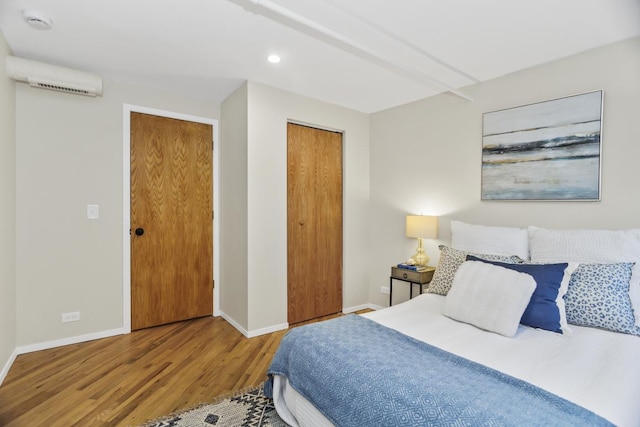 bedroom with a wall unit AC, a closet, and hardwood / wood-style flooring