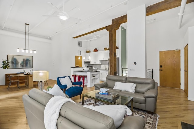 living room featuring a high ceiling, light hardwood / wood-style flooring, ceiling fan, and sink