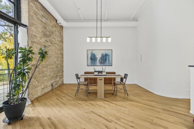 dining room featuring wood-type flooring, plenty of natural light, and brick wall