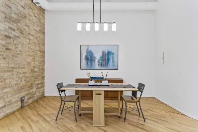 dining area featuring brick wall and light hardwood / wood-style floors