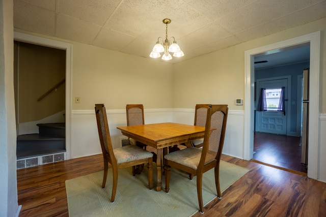 dining room with dark hardwood / wood-style flooring and an inviting chandelier