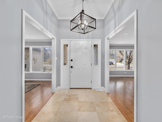 entryway with crown molding, light hardwood / wood-style flooring, and a notable chandelier