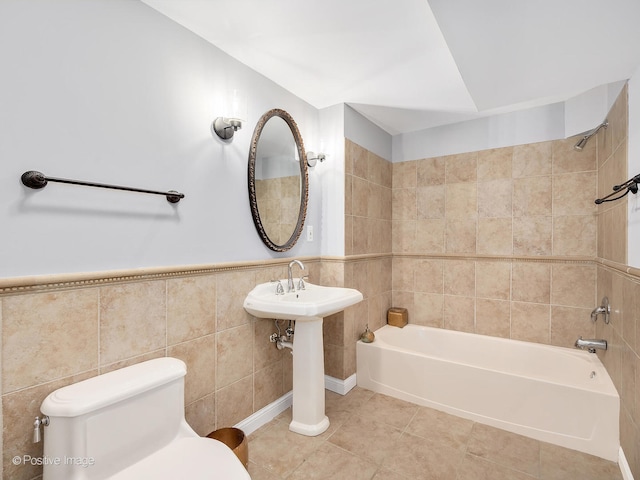 bathroom featuring toilet, tile patterned floors, tile walls, and tiled shower / bath