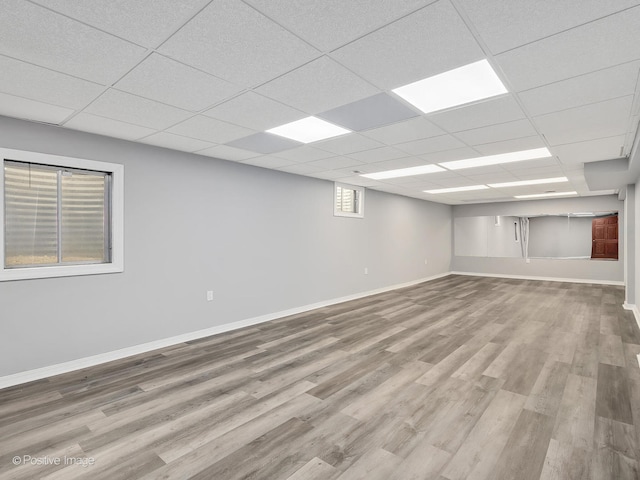 basement with a paneled ceiling and light wood-type flooring