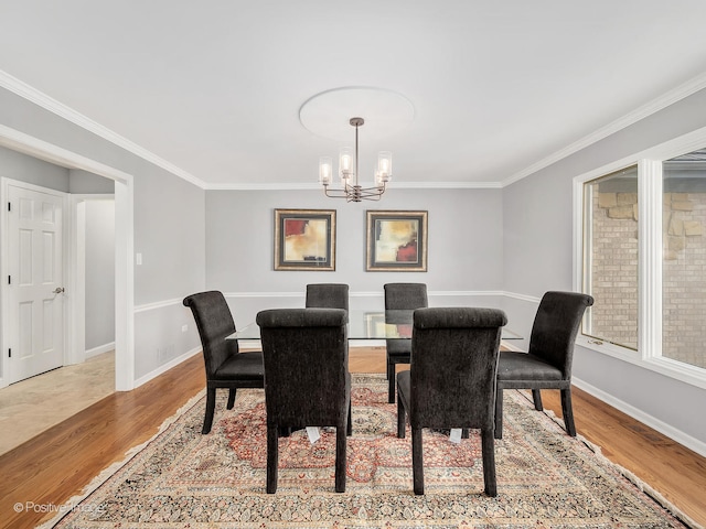 dining area with ornamental molding, hardwood / wood-style flooring, and an inviting chandelier