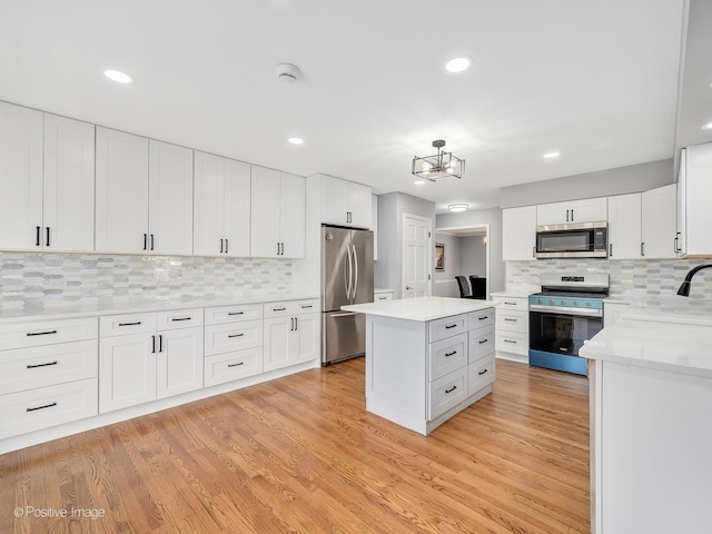 kitchen with light hardwood / wood-style floors, white cabinetry, stainless steel appliances, and a kitchen island