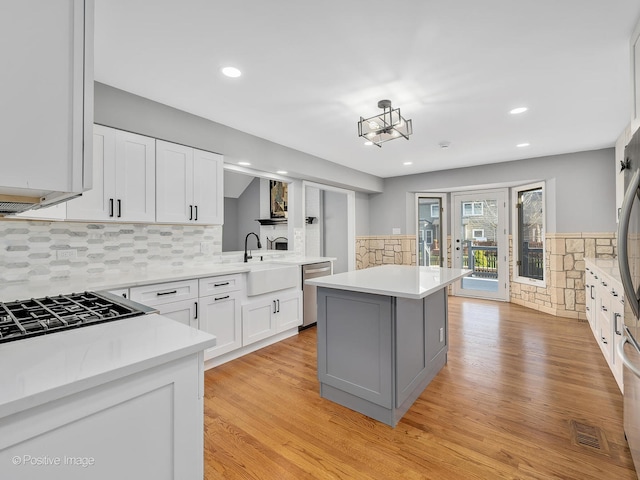 kitchen featuring light hardwood / wood-style flooring, white cabinetry, dishwasher, and a kitchen island