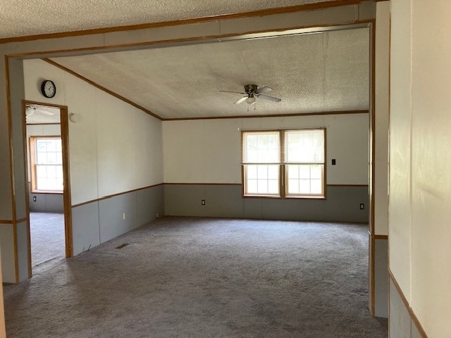 unfurnished room featuring light carpet, a textured ceiling, lofted ceiling, and ceiling fan