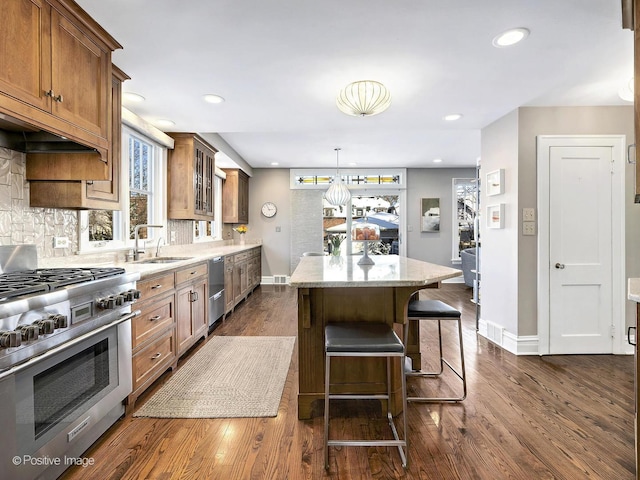 kitchen featuring sink, light stone counters, a center island, dark hardwood / wood-style floors, and stainless steel appliances