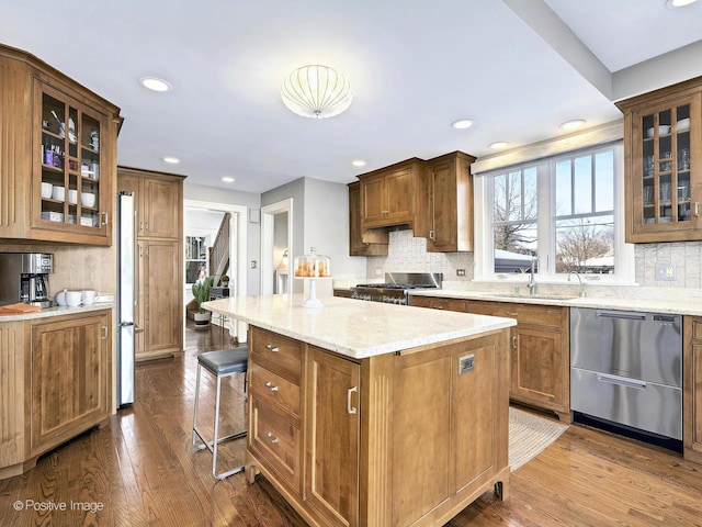 kitchen featuring wood-type flooring, stainless steel appliances, a kitchen island, and sink