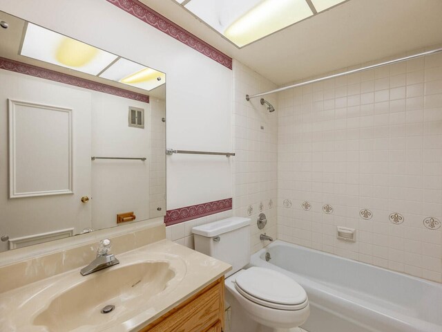 full bathroom featuring tiled shower / bath, vanity, and toilet