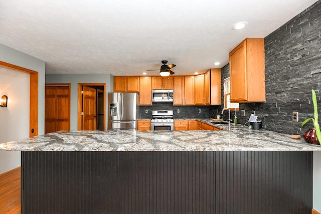 kitchen featuring kitchen peninsula, appliances with stainless steel finishes, and decorative backsplash