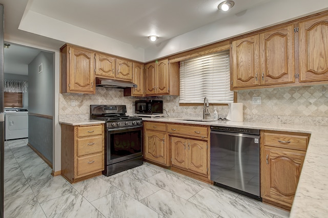 kitchen with independent washer and dryer, tasteful backsplash, black appliances, and sink