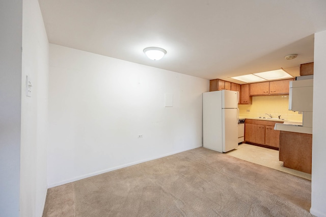 kitchen featuring tasteful backsplash, sink, white refrigerator, and light colored carpet