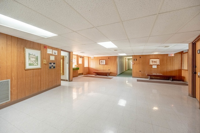 interior space with a paneled ceiling and wooden walls