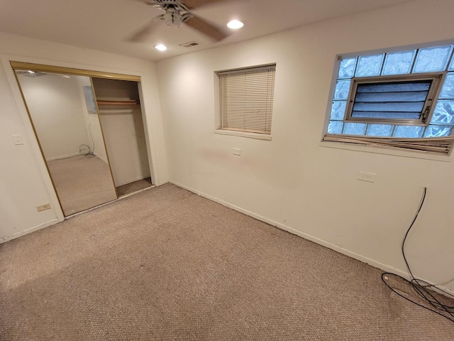 unfurnished bedroom featuring a closet, light colored carpet, and ceiling fan