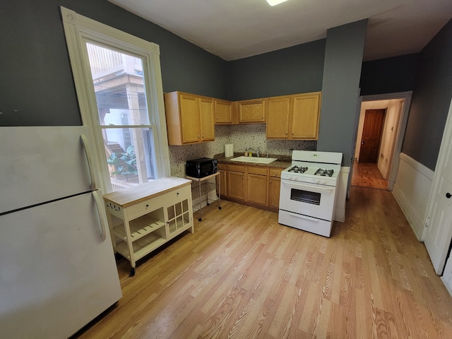 kitchen with white appliances, light brown cabinets, sink, backsplash, and light wood-type flooring