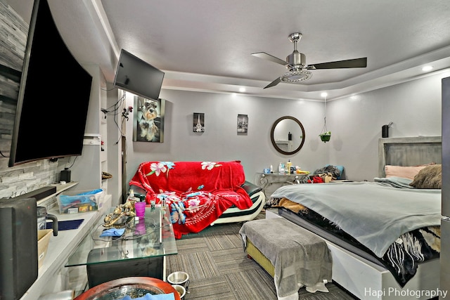 carpeted bedroom featuring a raised ceiling and ceiling fan