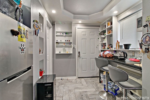 home office with a tray ceiling and light parquet floors