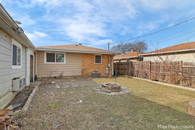 back of property featuring a yard, central AC, and a fire pit