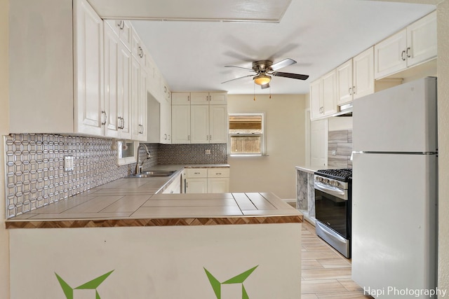 kitchen featuring sink, gas stove, kitchen peninsula, white fridge, and backsplash