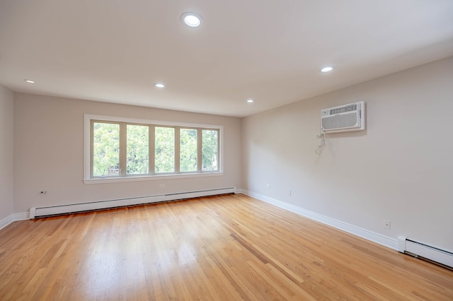 unfurnished room with a wall unit AC, a baseboard heating unit, and light wood-type flooring