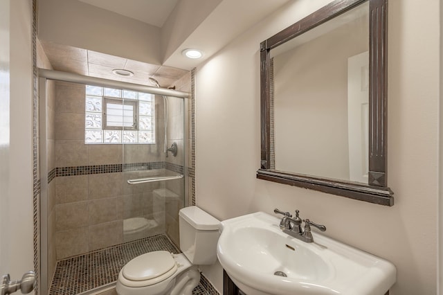 bathroom with sink, a shower with shower door, and toilet