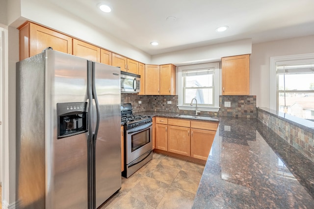 kitchen featuring dark stone countertops, backsplash, appliances with stainless steel finishes, and sink