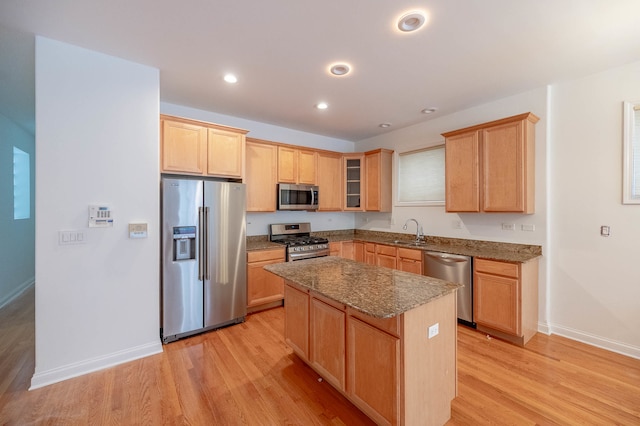 kitchen with appliances with stainless steel finishes, a center island, sink, and light hardwood / wood-style floors