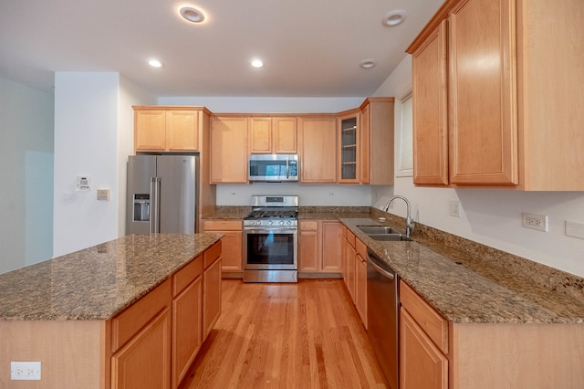 kitchen featuring stainless steel appliances, dark stone countertops, sink, light brown cabinetry, and light hardwood / wood-style floors