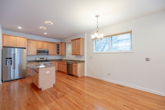 kitchen with stone countertops, sink, a center island, light wood-type flooring, and appliances with stainless steel finishes